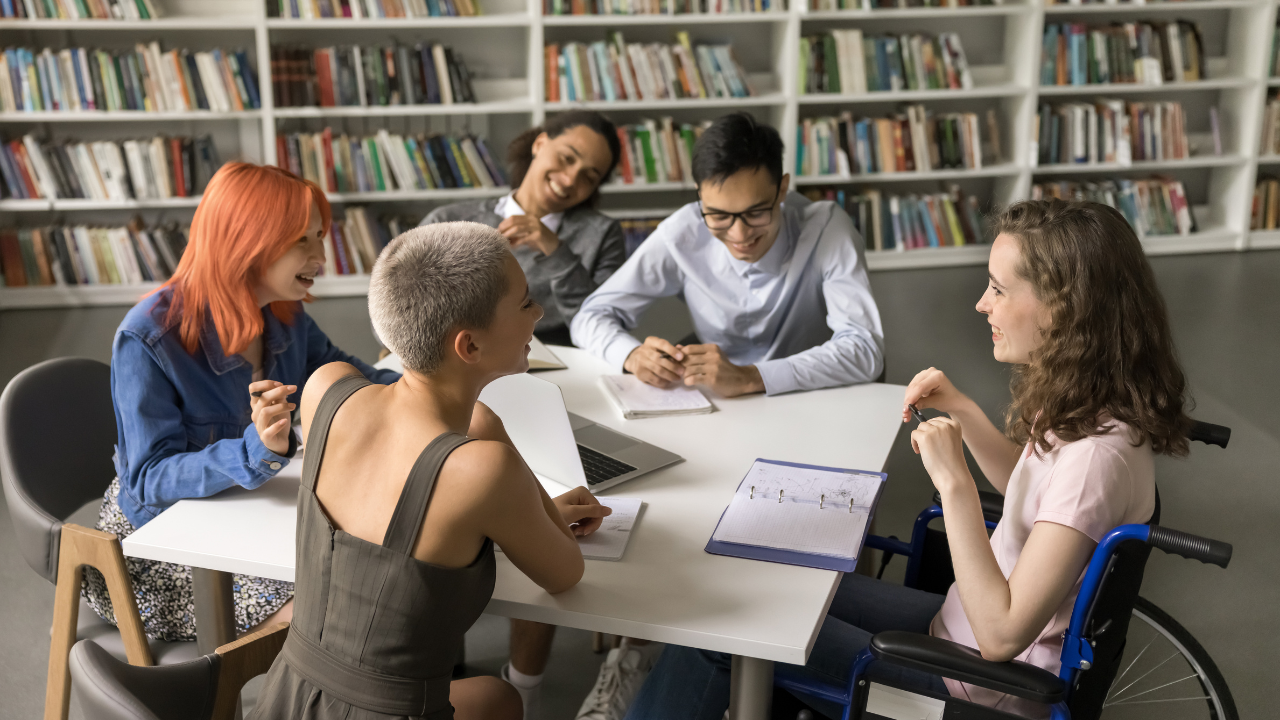 Lernende lösen eine Gruppenarbeit in einer Bibliothek während dem ÜK